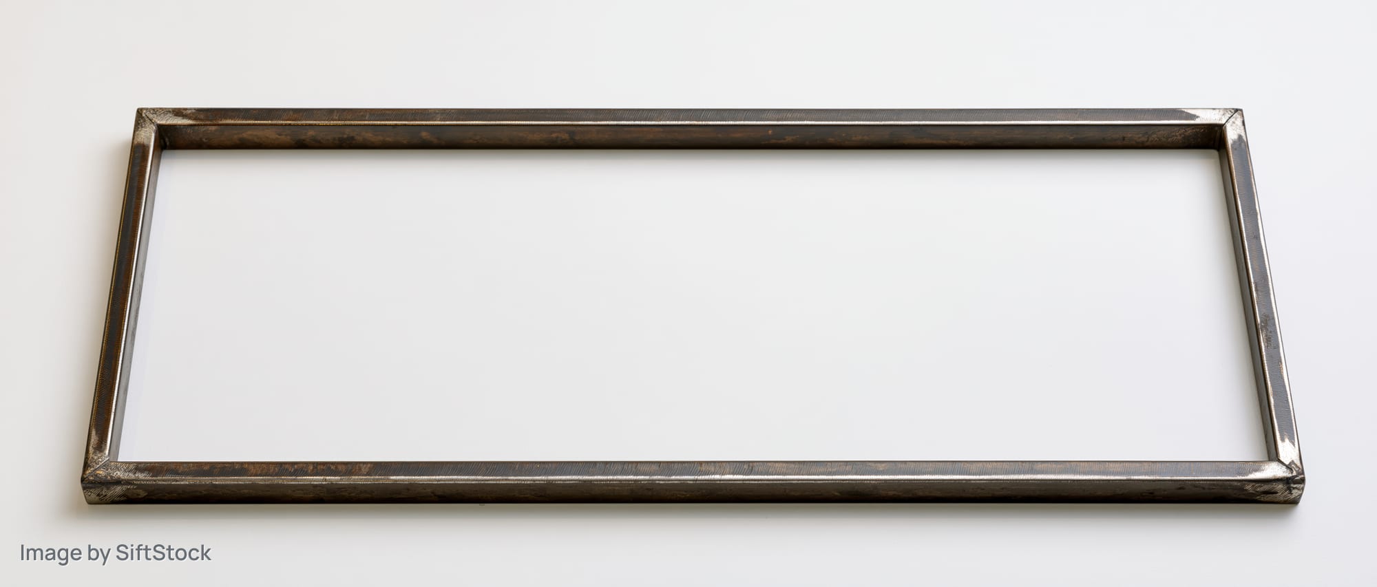 Thin rectangular metal frame lying flat on white surface