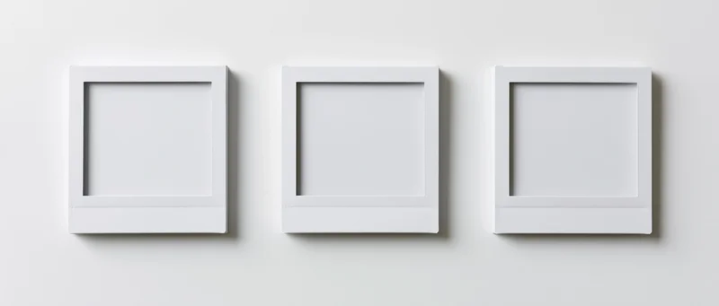Three blank instant photo prints arranged side by side on a white wall