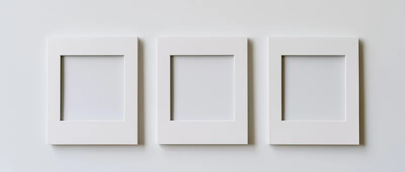 Three white blank photo frames arranged side by side on a plain wall