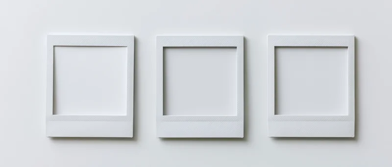 Three blank instant photo prints arranged side by side on a white wall