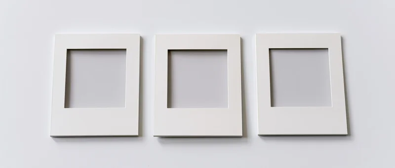 Three white blank instant photo frames arranged side by side on a plain wall