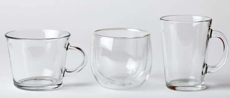 Three empty clear glass mugs arranged in a row on a white surface