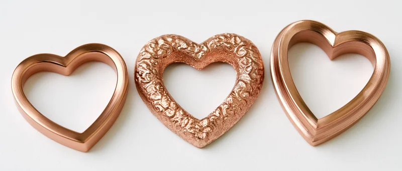 Three heart-shaped copper decorative frames arranged side by side on white surface