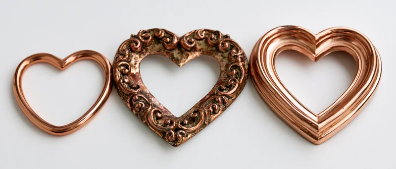 Three copper heart-shaped decorative frames arranged side by side on white background