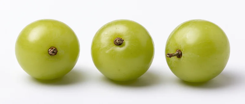 Three green grapes in a row on a white surface
