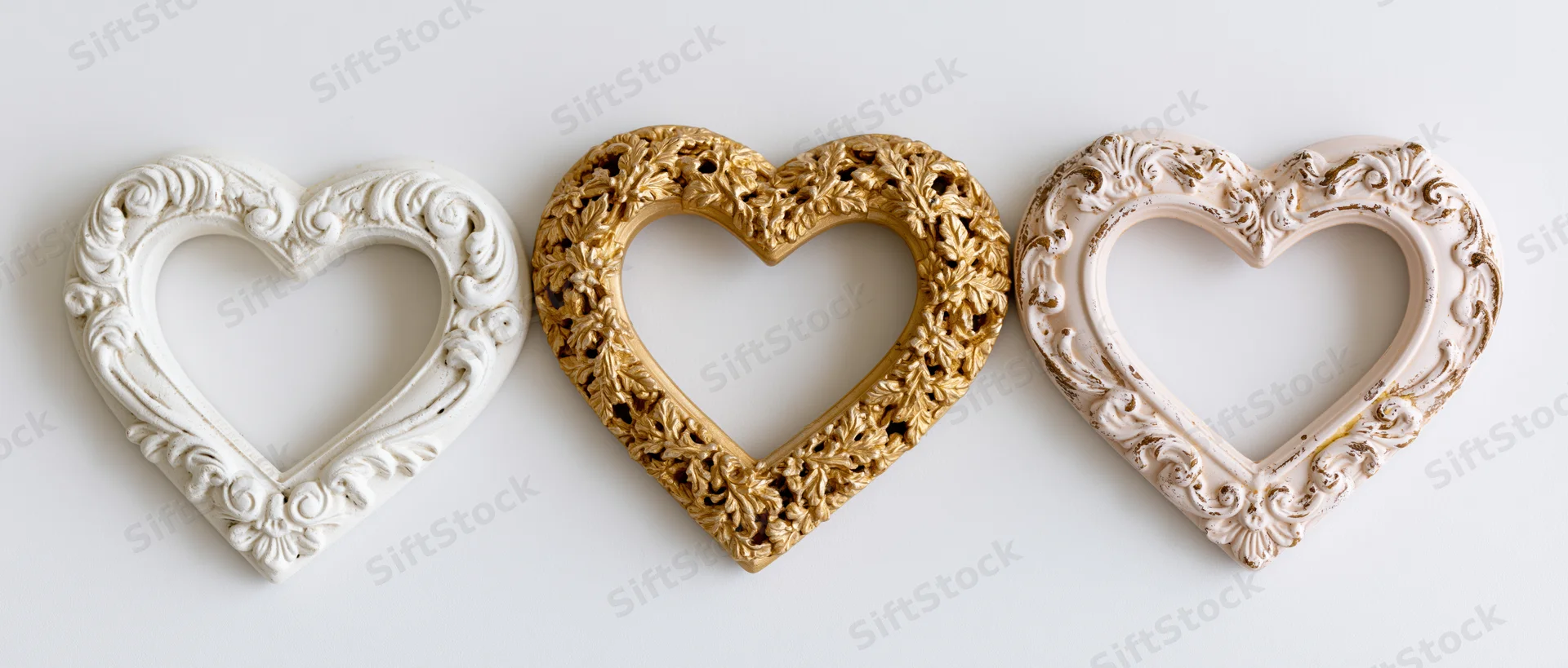 Three ornate baroque heart-shaped frames arranged side by side on a white surface