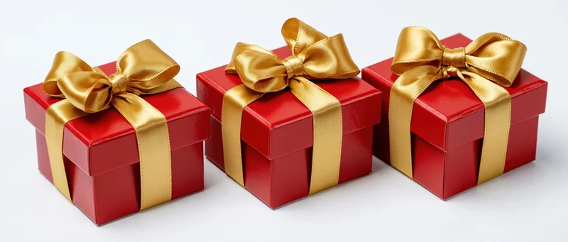 Three red gift boxes with gold satin ribbons and bows arranged in a row on white background