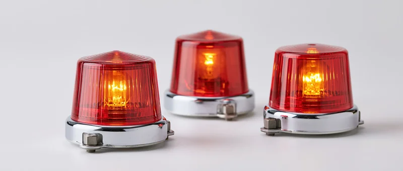 Three red industrial warning beacon lights arranged side by side on a white surface