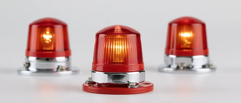 Three red industrial warning beacon lights arranged side by side on a white surface