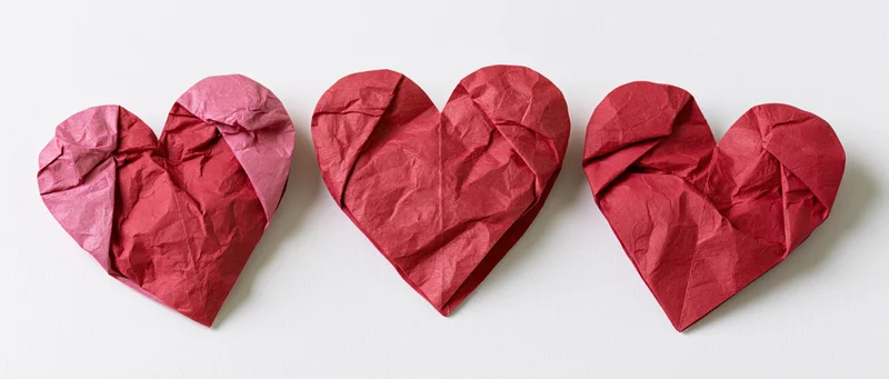 Three red paper hearts arranged in a row on white background
