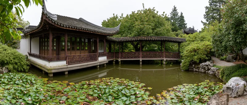 Traditional chinese garden with wooden pavilion over a pond surrounded by lotus plants and trees