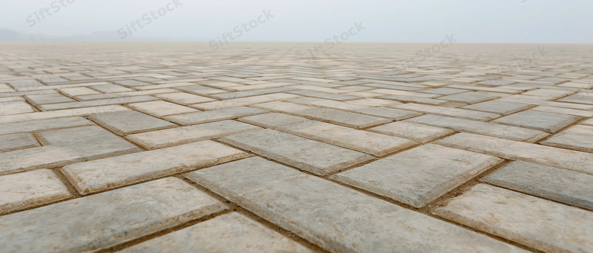 Herringbone-patterned concrete brick pavement in a vast open public plaza
