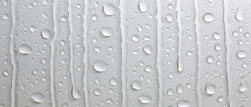 Water droplets and streaks on a clean white glass surface