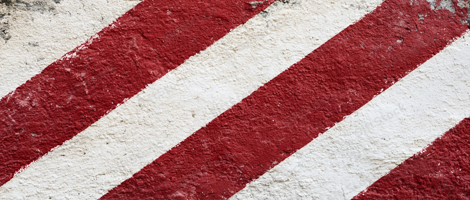 Weathered concrete wall with bold diagonal red and white stripes