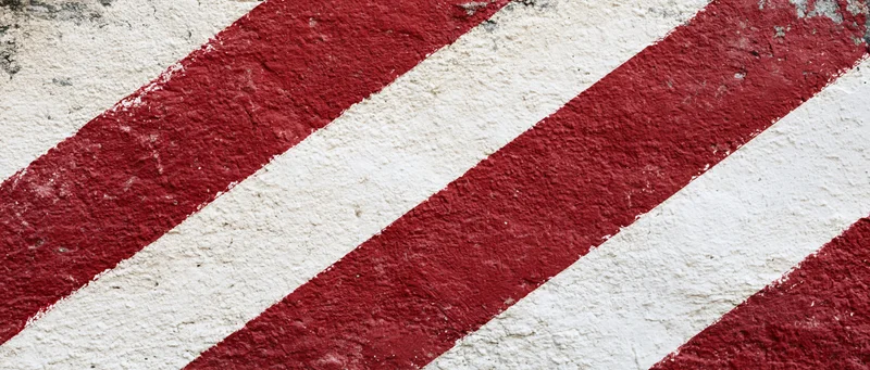 Weathered concrete wall with bold diagonal red and white stripes
