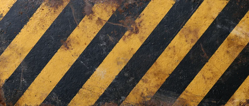 Weathered diagonal yellow and black hazard stripes on an industrial floor surface