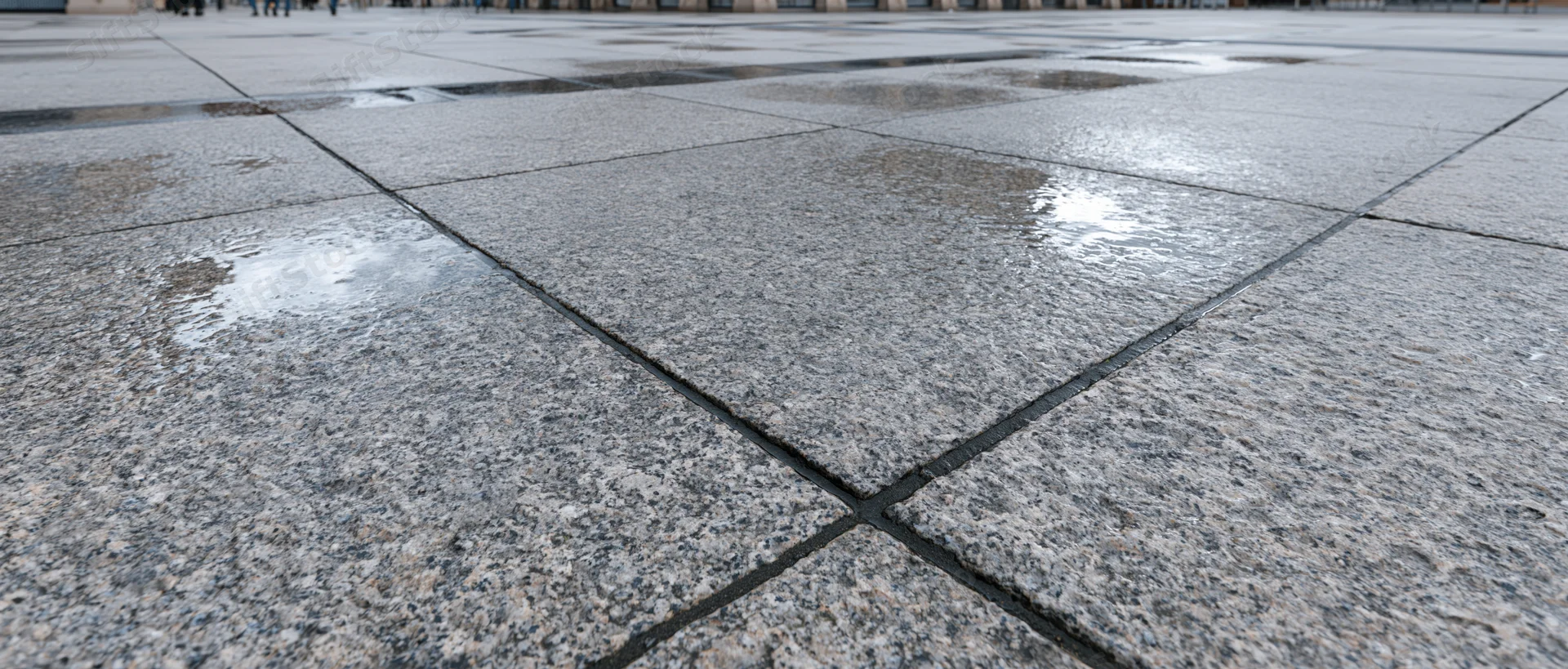 Wet granite paving stones in an empty outdoor plaza viewed from low angle
