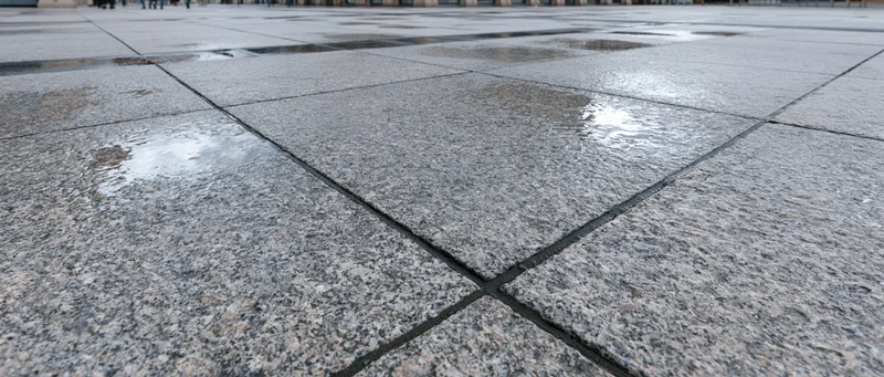 Wet granite paving stones in an empty outdoor plaza viewed from low angle