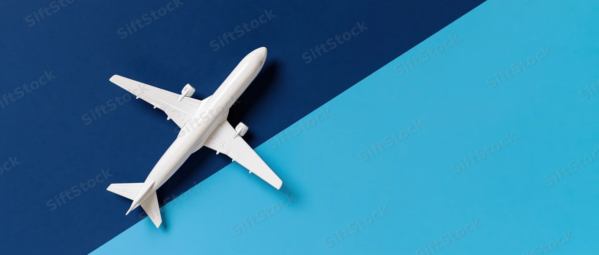 White commercial airplane model viewed from above on blue background
