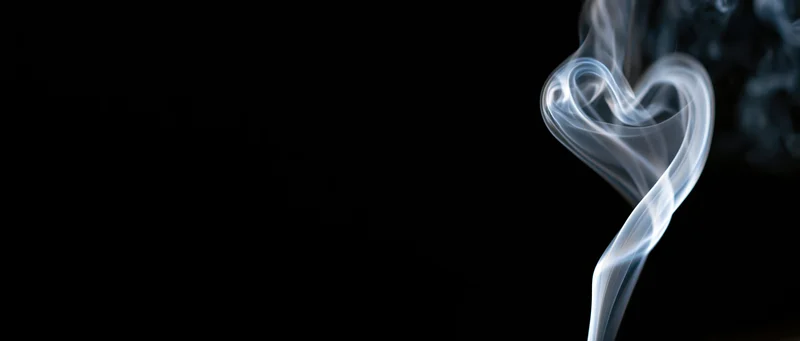 White smoke curling into a heart shape against a black background