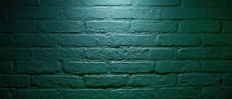 Painted brick wall filling the frame with green texture and spotlight lighting
