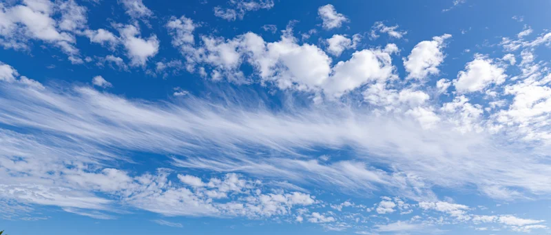 Wide panoramic view of a clear blue sky with scattered white clouds