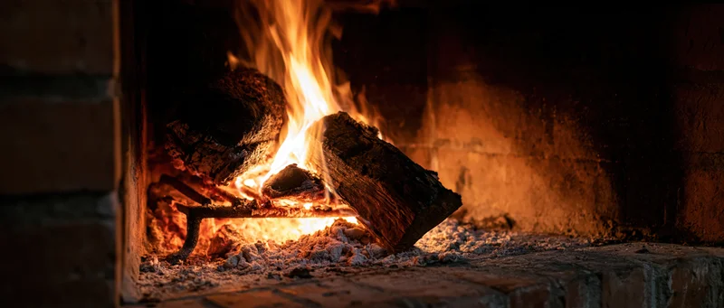 Burning wood logs in a brick fireplace at night