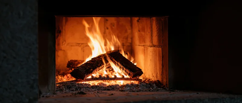 Burning wood logs in a brick fireplace at night
