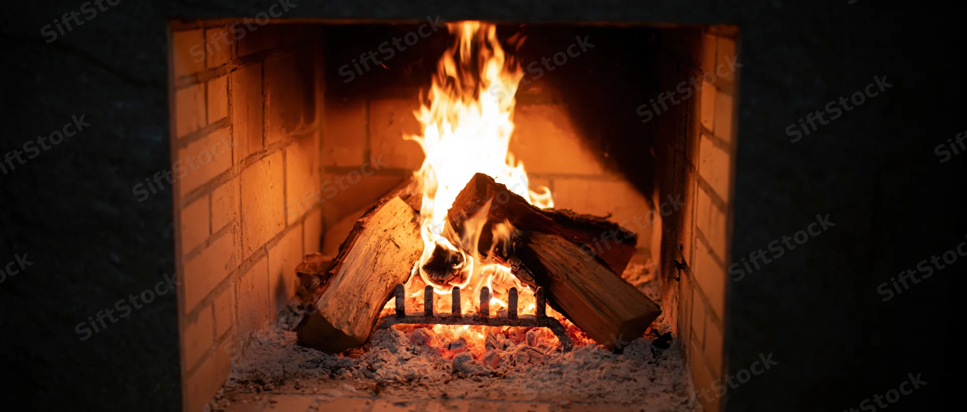 Wood logs burning in a square brick fireplace at night