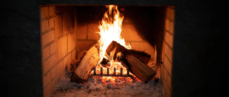 Wood logs burning in a square brick fireplace at night