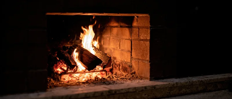 Burning wood logs in a square brick fireplace at night