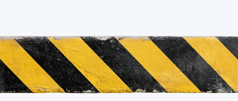 Worn black and yellow diagonal hazard stripes on a concrete barrier isolated on white