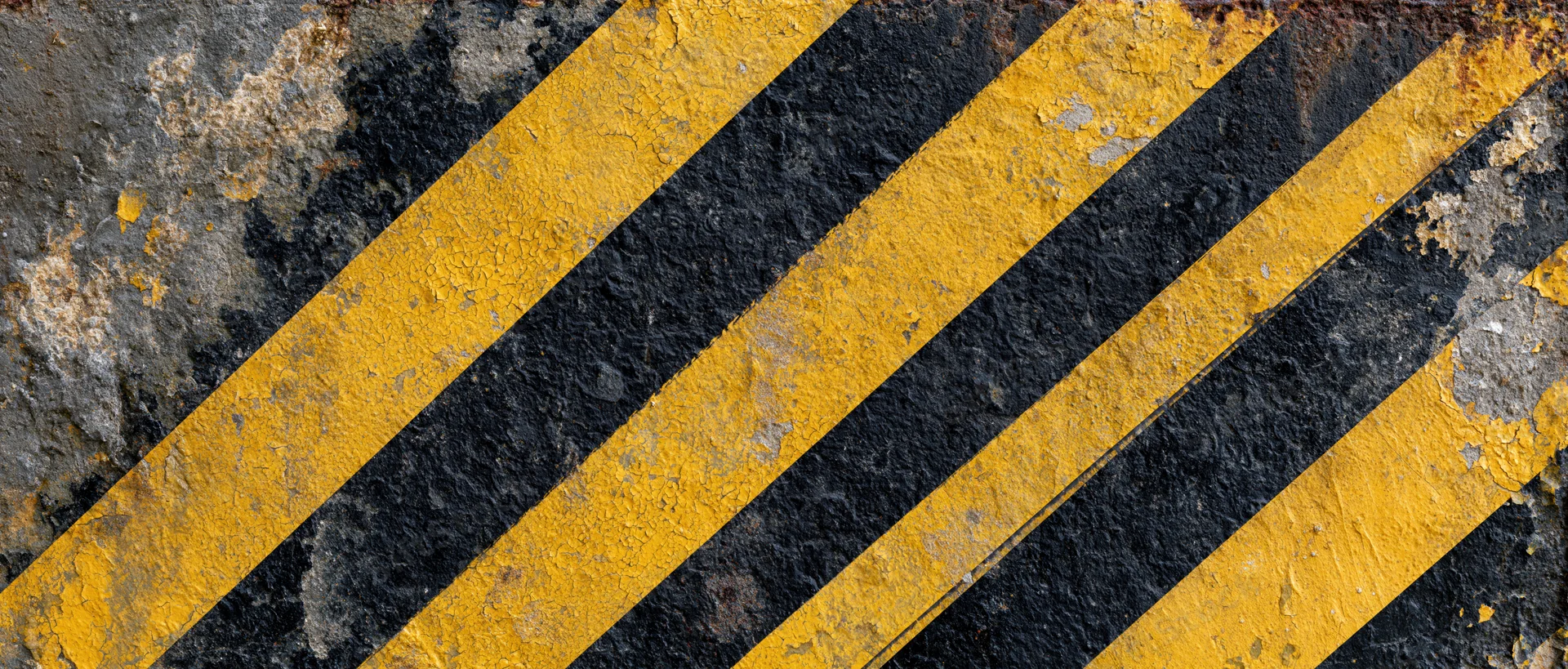 Diagonal black and yellow hazard stripes on a worn concrete surface