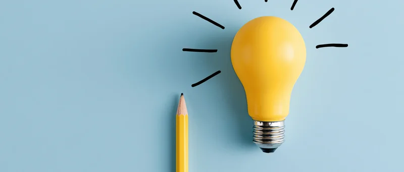 Yellow lightbulb and sharpened yellow pencil on blue surface