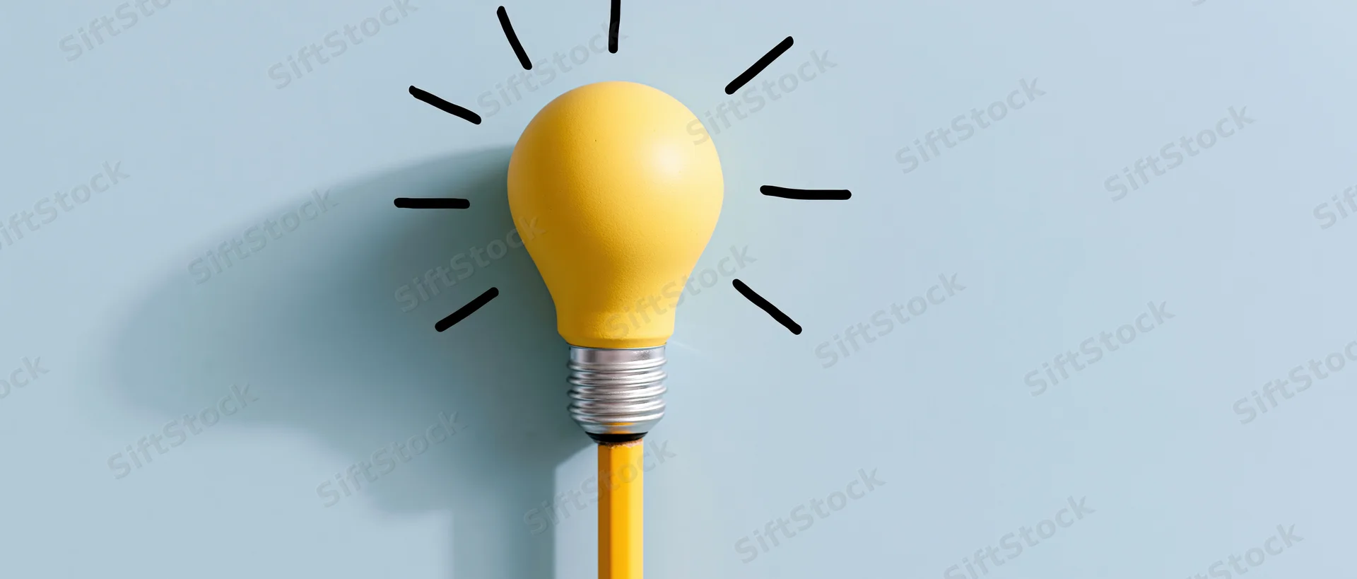 Yellow lightbulb resting on top of a yellow pencil against a blue background