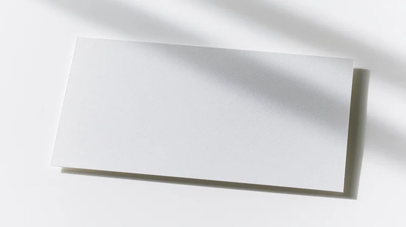 Blank white card lying flat on a white surface with soft shadows