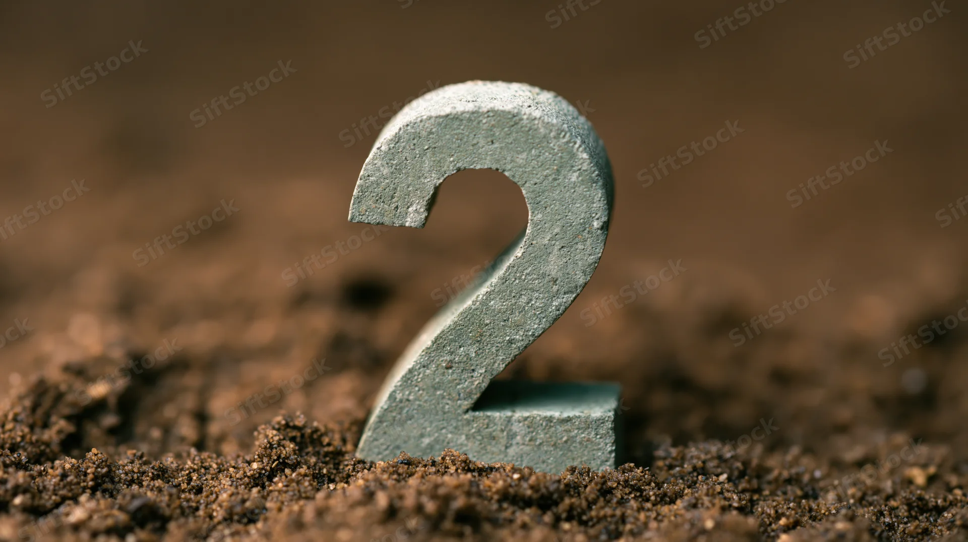 Concrete number two standing upright in soil