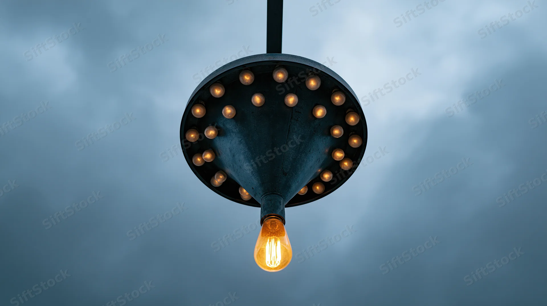 Vintage industrial pendant lamp with glowing edison bulb hanging against cloudy sky