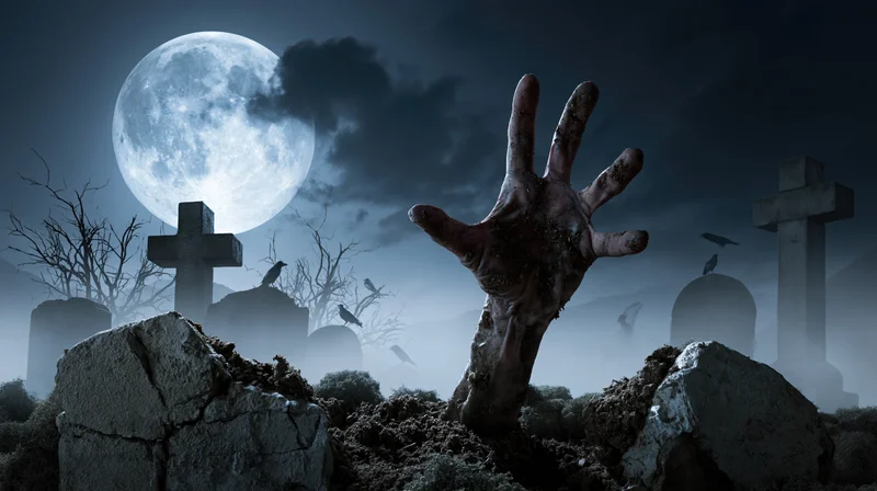 Decayed hand clawing from broken grave in foggy cemetery under full moon