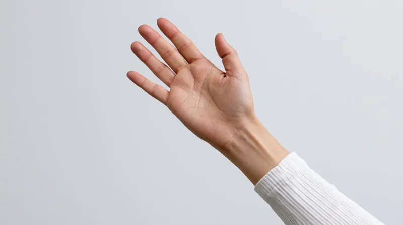 Hand raised upward with palm facing forward against light neutral background