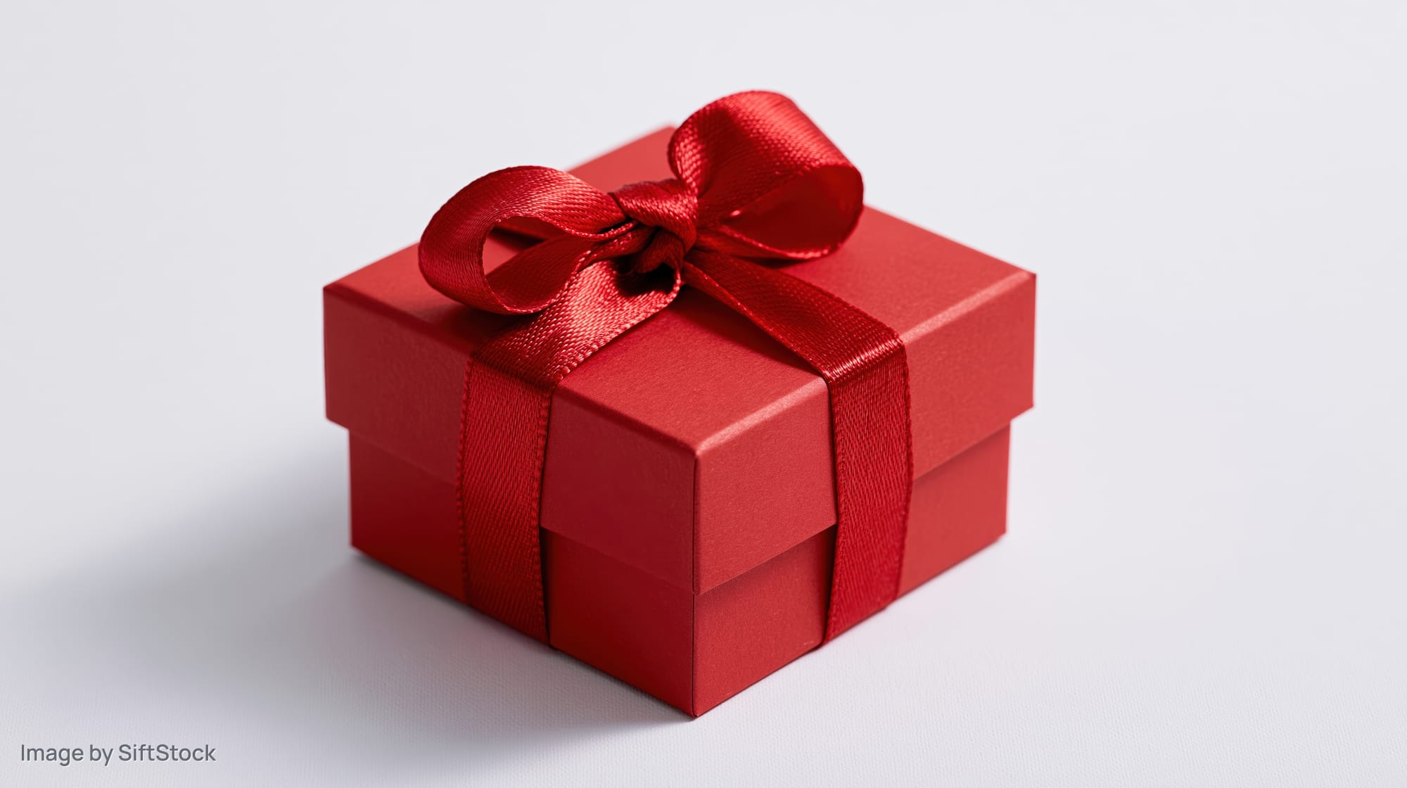 Red gift box with satin ribbon bow on white background