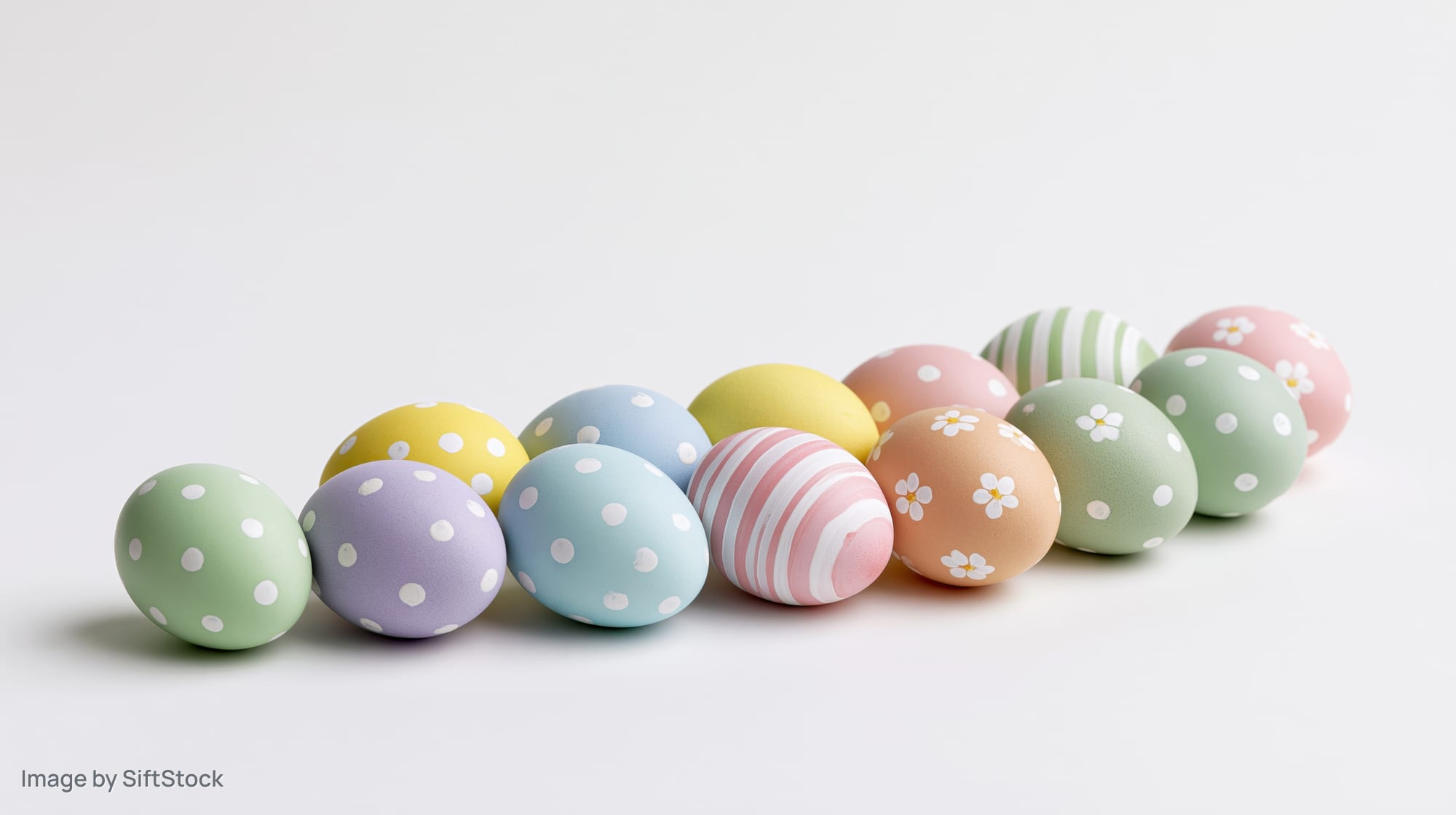 Pastel decorated easter eggs arranged in a row on white background