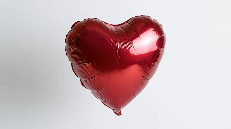 Shiny red metallic foil heart-shaped balloon floating against white background