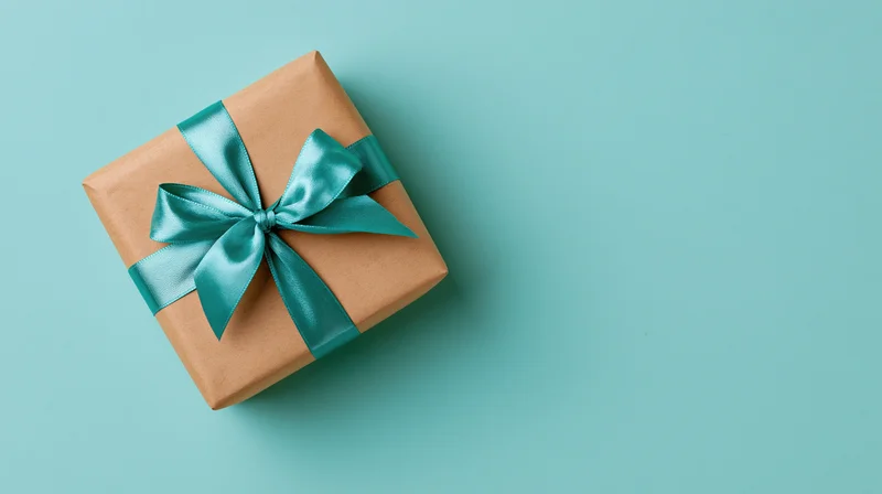 Gift box wrapped in brown kraft paper with teal ribbon bow on teal background
