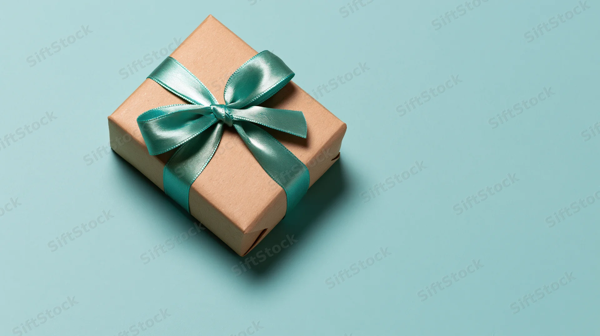 Gift box wrapped in brown kraft paper with teal ribbon bow on blue background