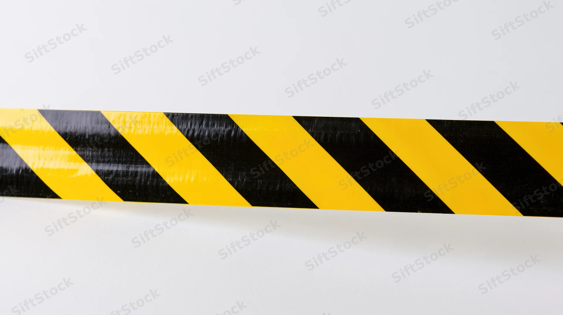 Horizontal strip of yellow and black diagonal hazard tape on white background