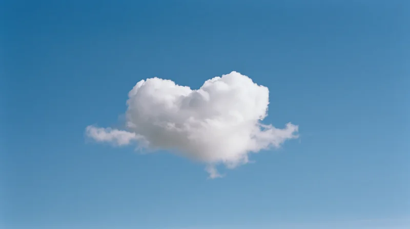 Heart-shaped cloud floating in a clear blue sky