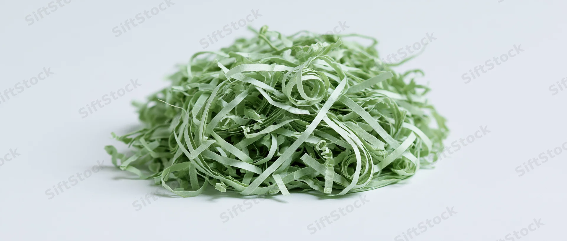 Pile of green shredded paper Easter grass filler on white background