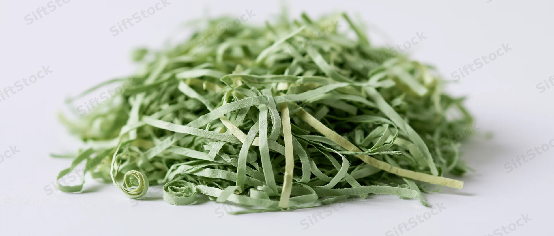 Pile of green shredded paper Easter grass filler on white background