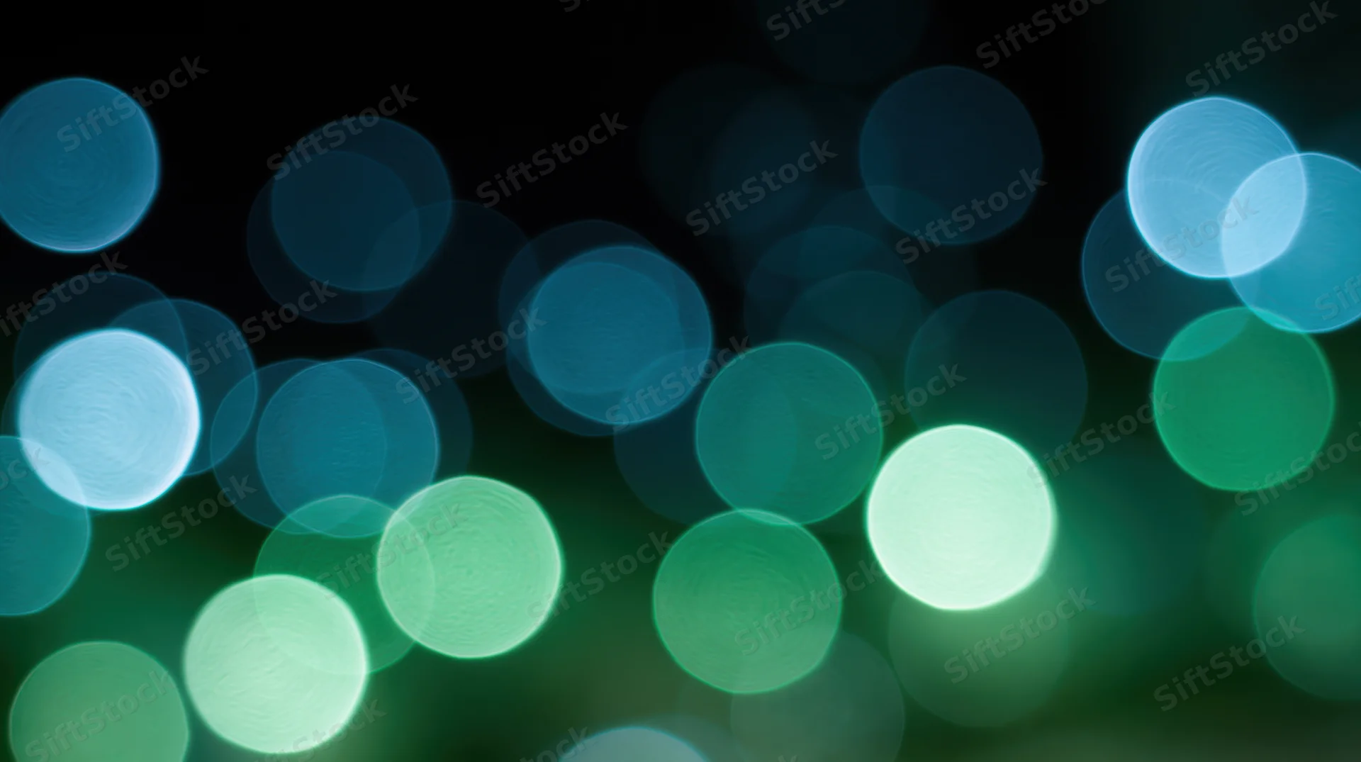 Abstract bokeh lights in green and blue tones against dark background